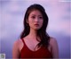 A woman in a red dress standing in front of a cloudy sky.