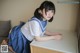 A woman in a school uniform sitting at a desk.