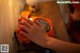 A woman's hand on an orange telephone on a table.