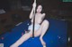 A naked woman sitting on a pool table holding a cue.