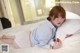 A woman laying on a bed holding a strawberry.