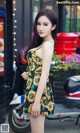 A woman in a sunflower print dress posing for a picture.