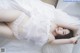 A woman laying on a bed in a white lingerie.