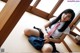 A woman in a school uniform sitting on the floor.