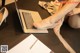 A woman sitting at a desk with a laptop and a pen.