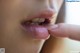 A close up of a woman's mouth with her finger on her lips.